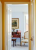 Gold chair and antique writing desk viewed through doorway in Northern home, UK