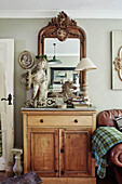 Cherub statue and lamp on wooden sideboard with mirror in Somerset home, UK