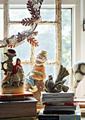 Garden gnome and figurines with books on Somerset windowsill, UK