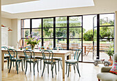 Dining table and chairs in garden extension with view to garden in Oxfordshire extension, UK
