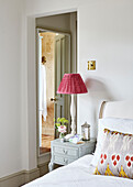 Bedside lamp with ensuite reflected through doorway in Oxfordshire home, UK