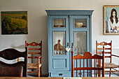 Upcycled glass cabinet and dining chairs with artwork in North Yorkshire farmhouse, UK