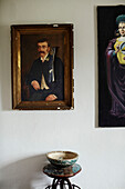 Ripped artwork above stool with bowl in North Yorkshire farmhouse, UK