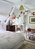 Quilted bed cover and bunting in attic bedroom of Oxfordshire farmhouse, UK