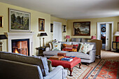 Framed artwork and grey sofas with lit fire in North Yorkshire farmhouse, UK