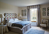 Floral headboard and striped curtains with grey blanket and bedside lamps in North Yorkshire farmhouse, UK