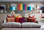 Helle Kissen auf beigem Sofa mit türkisfarbenen Lampen und moderner Kunst in offener Londoner Wohnung, UK