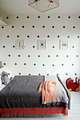 Graue Decke auf dem Bett mit Kreuzmustertapete in einem Neubau in Sligo, Irland