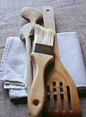 Hölzerne Küchenutensilien, darunter Pfannenwender, Backpinsel und Holzlöffel
