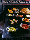 Gedeckter Tisch mit marokkanischen Köstlichkeiten, darunter verschiedene Gemüsesorten mit Chermoula,Tomatenmarmelade, Zaalouk, Oliven und Brot