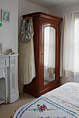 Evening dress hangs on wooden mirrored wardrobe in bedroom of Colchester family home, Essex, England, UK