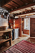 Küche mit offener Tür und rot gemustertem Teppich in einer Holzhütte in den Bergen von Sirdal, Norwegen