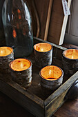 Teelichter in Birkenrind auf einem Holztablett in der Küche einer Holzhütte in den Bergen von Sirdal, Norwegen