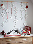Snowflake wall decoration and pop-up Christmas book on chest of drawers in family home, Poland