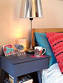 Blue bedside table with silver lampshade in family home, France