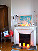 Lit candles at fireplace with Philippe Starck chair in family home, France