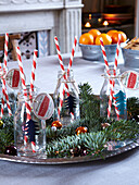 Red and white striped straws in bottles with pine needles and baubles in family home, France