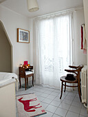 Holzstuhl im Vintage-Stil, Spitzenvorhänge und neuartiger Badvorleger im Badezimmer eines modernen Familienhauses in Frankreich