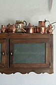 Collection of antique copper coffee pots on kitchen cupboard