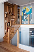 Wooden staircase with glass ballustrade and built in shelves in renovated Georgian apartment in St Leonards on Sea, East Sussex, UK