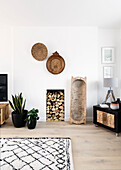 Afrikanisches Geschirr an der Wand, Brennholz, Zimmerpflanzen und Schrank im Wohnzimmer in Reigate, Surrey, UK