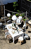 Solar lanterns above table with wooden seating and cushion fabrics in Colchester terrace, Essex, UK