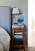 Wooden bedside stool with lamp books and small vintage suitcase in Colchester, Essex, UK