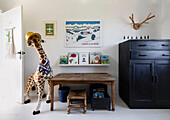 Vintage cupboard painted Graphite and school desk with toys and books in boy's room in Colchester home, Essex, UK