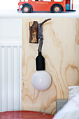 Plywood headboard with lamp hanging on hook of wood in boy's room in Colchester, Essex, UK
