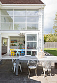 Sunlit table and chairs on terrace of double height extension Guildford home, Surrey, UK