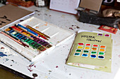Malkasten und Bleistifte mit Farbkarte auf dem Schreibtisch eines Künstlers Brighton, East Sussex UK