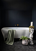 Vintage stoneware pieces make a bold statement in the bathroom and contrast with the modern bath against the dark walls