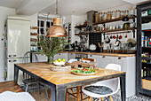 Wohnküche mit Holztisch und verschiedenen Stühlen sowie offenen Regalen mit Einmachgläsern und Küchenutensilien, Cardiff, Wales, UK