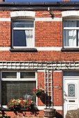 Exterior of Victorian red brick terrace house with window box and hanging plants Cardiff Wales UK