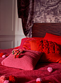 Double bed in bedroom with colourful blanket bedspread pillows and textured cushions
