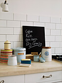 Kitchen side board with shopping list written on blackboard and kitchen storage containers displayed