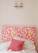 Pretty crocheted lamps above a flowery printed headboard in a white bedroom
