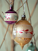 Two decorative glass Christmas baubles hanging on twigs