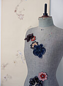 Vintage tailors dummy with floral fabric brooches pinned on 