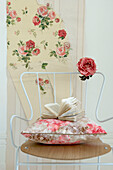 White metal and wood chair with floral wallpaper and fabric samples