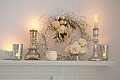 mantelpiece with Christmas decorations glowing candles flower arrangement and wreath
