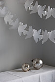 Two silver baubles and a paper dove garland