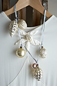 White evening dress handing on a ladder with silver and gold christmas bauble garlands detail