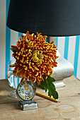 Black lampshade on wood table with cut flower and date reminder