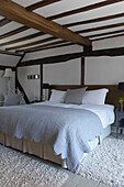 Hellblaue gesteppte Bettdecke in einem Schlafzimmer mit Balkendecke im Landhausstil in Hastings