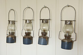Hurricamne lamps hang on tongue and groove panelling in Hastings beach house England UK