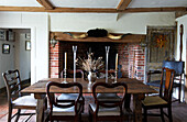 Antiker Esstisch und freiliegender Backsteinkamin in einem Bauernhaus in Iden, Rye, East Sussex, Vereinigtes Königreich