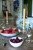 Peaches and plums with silver candlesticks on dining table in Massachusetts home, New England, USA