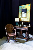 Antique carved wooden table and chair in dark blue bedroom of Massachusetts home, New England, USA