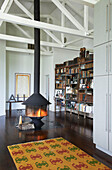 Freestanding lit fire and bookcase with patterned rug in Sheffield home, Berkshire County, Massachusetts, United States